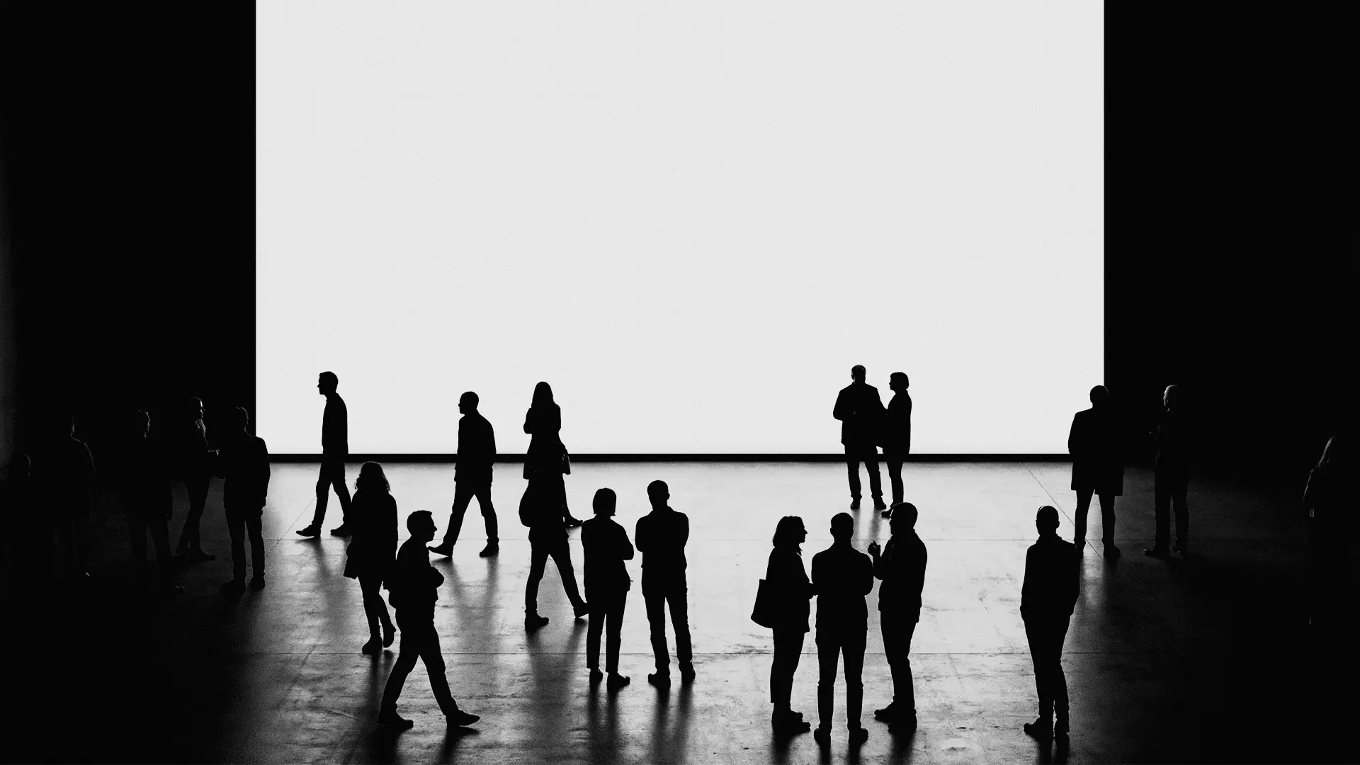 Gruppo di persone in silhouette davanti a un grande schermo bianco vuoto