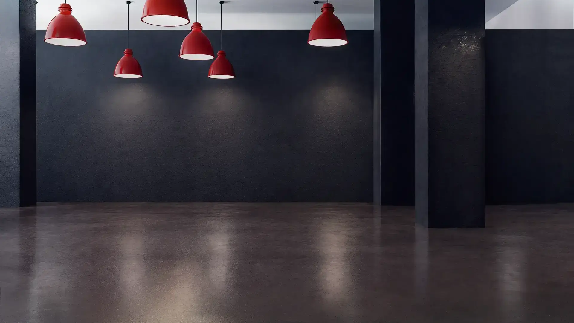 Spazio industriale vuoto con parete scura e lampade a sospensione rosse accese